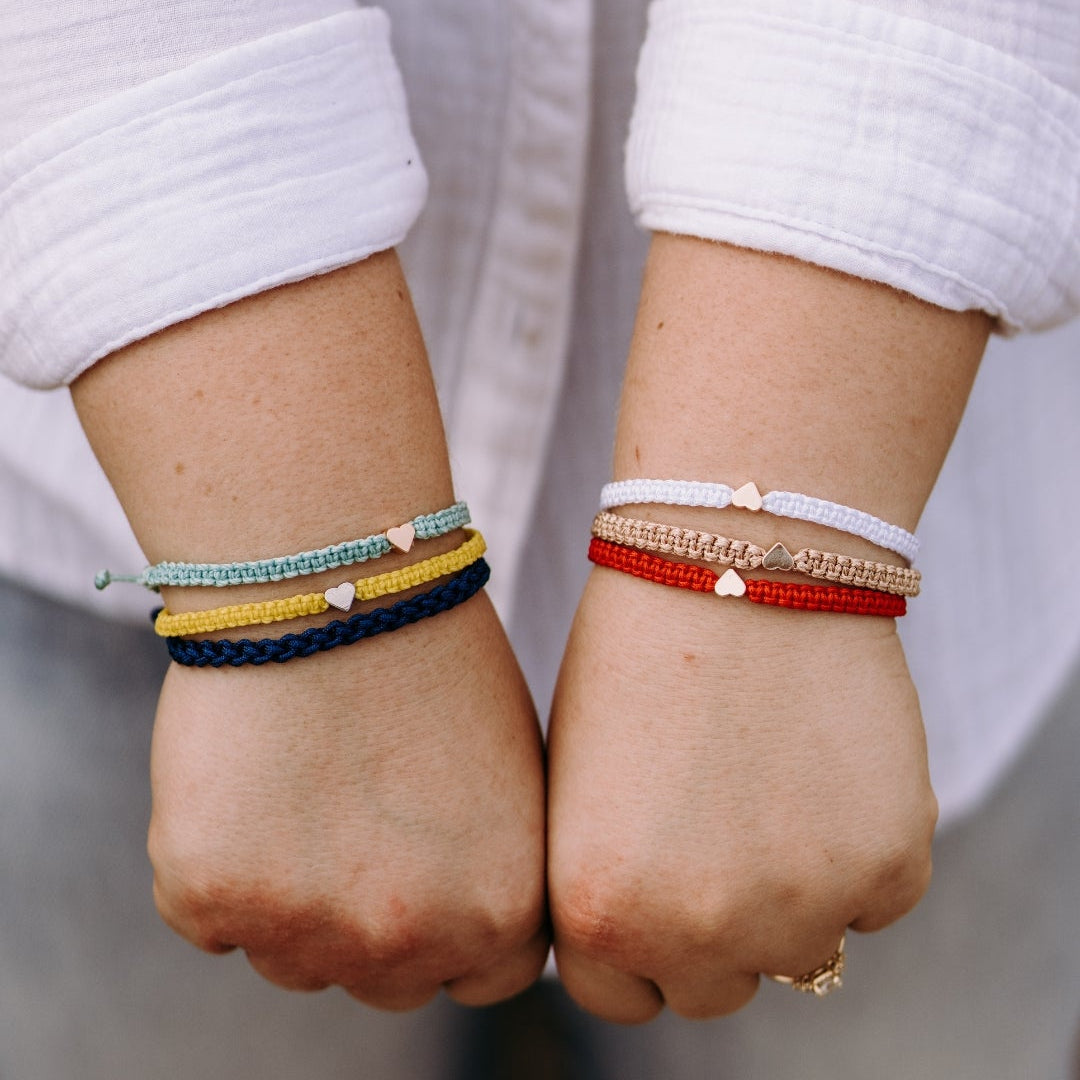 Two hands wearing colorful bracelets 