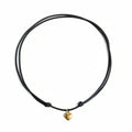 Black cord necklace with a gold heart charm on a white surface