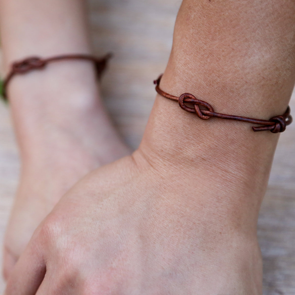 Close-up of a person's wrist wearing a brown leather bracelet 