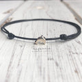 A black cord anklet bracelet featuring a sterling silver dolphin charm. The bracelet has a minimalist design.