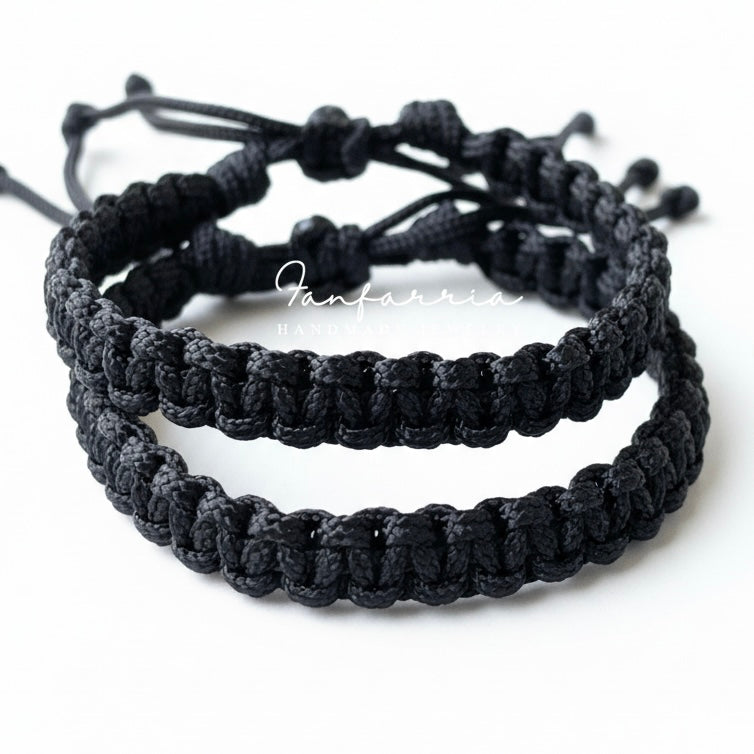 Two black braided bracelets stacked on a white background 