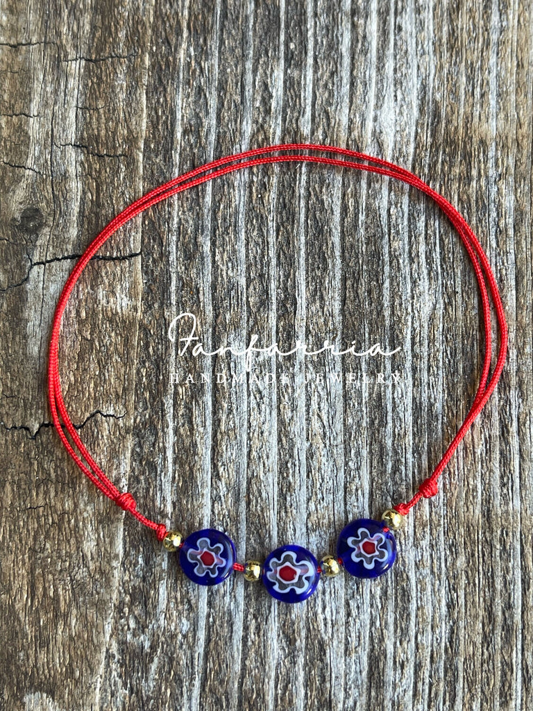 Handmade adjustable red cord bracelet featuring three blue millefiori glass flower beads with gold accents
