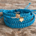 Turquoise blue family matching bracelets with gold heart charms. The bracelets are stacked on top of each other.