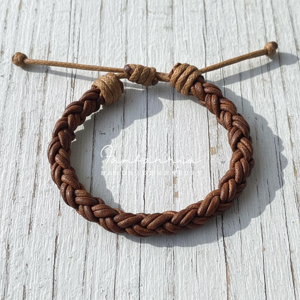 Handmade braided brown leather bracelet with adjustable cord on a rustic white wooden surface.