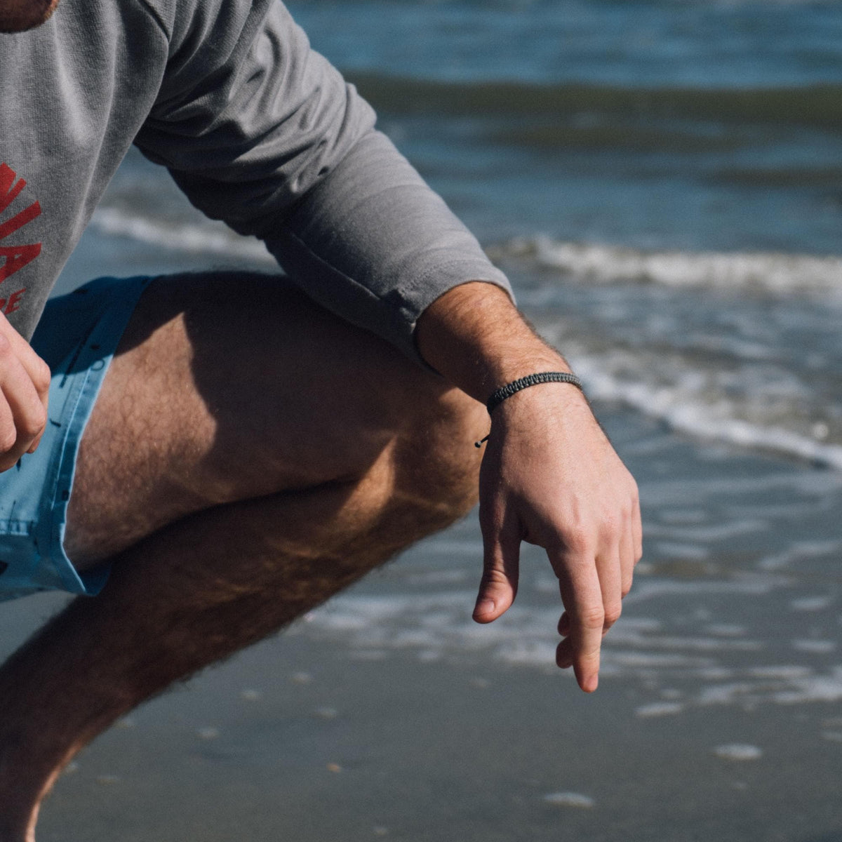 Person with macrame bracelet with ocean waves in the background