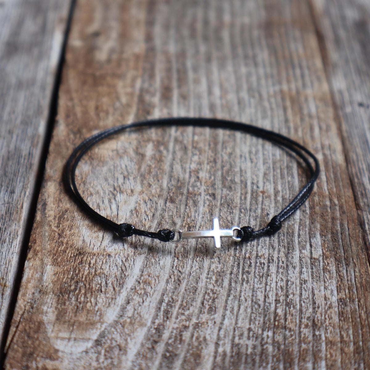 Black waxed cord bracelet with silver-tone sideways cross charm, 8x20mm
