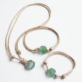Handmade surfer sea glass jewelry set, necklace, anklet, and bracelet with turquoise glass beads on natural waxed cord, shown on driftwood background