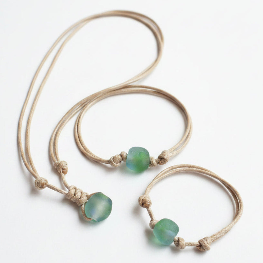 Handmade surfer sea glass jewelry set, necklace, anklet, and bracelet with turquoise glass beads on natural waxed cord, shown on driftwood background
