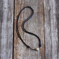 Sterling silver heart necklace with adjustable black cord, displayed on rustic wood background