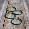 Green waxed cord matching bracelet set for family, four adjustable knot bracelets displayed on wood background