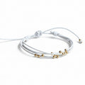 White leather wrap bracelet with gold beads on rustic wood background