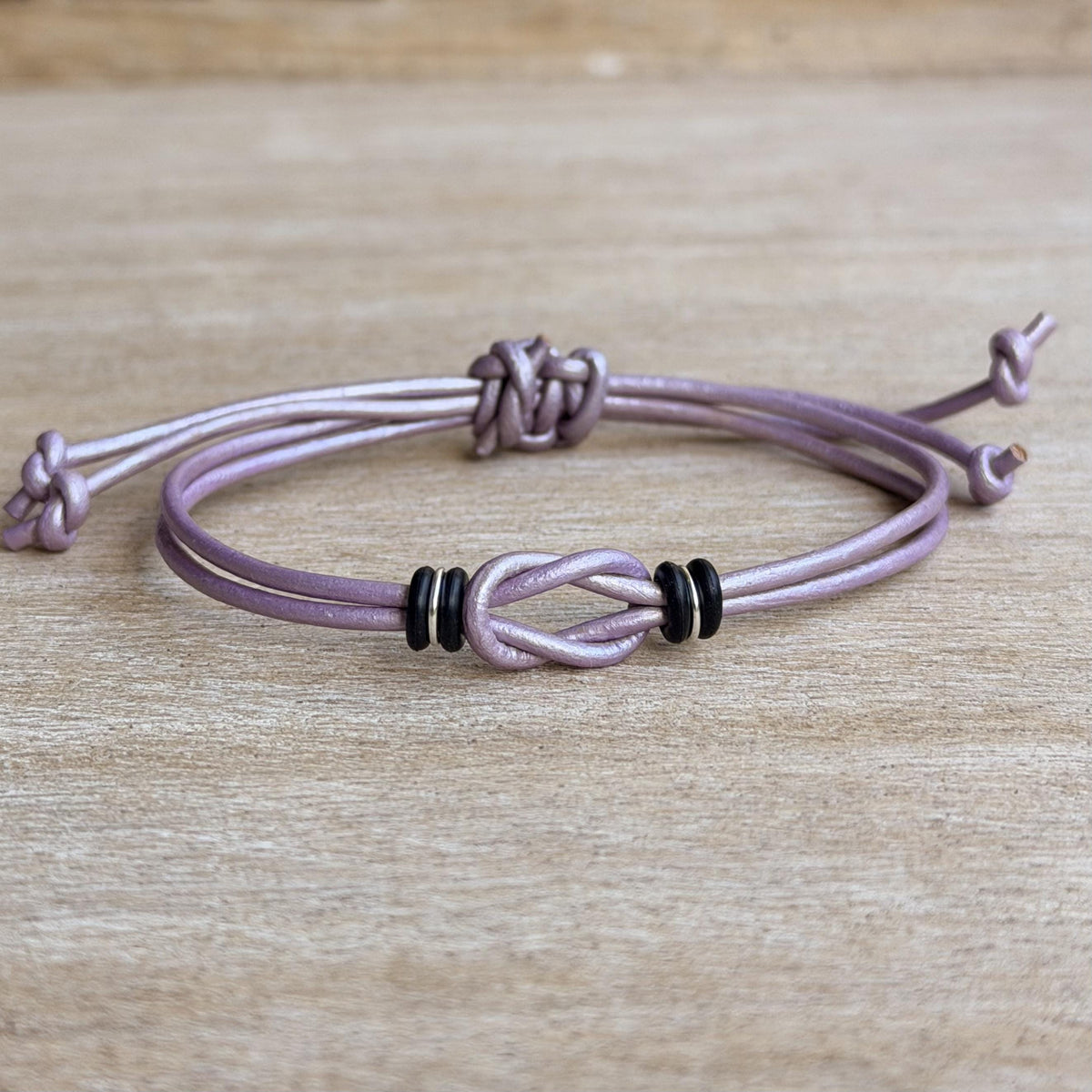 Lavender leather Celtic knot bracelet with black and silver accents, featuring a double-wrap design and adjustable closure. Handmade boho leather bracelet for women, perfect for everyday wear or a meaningful gift.