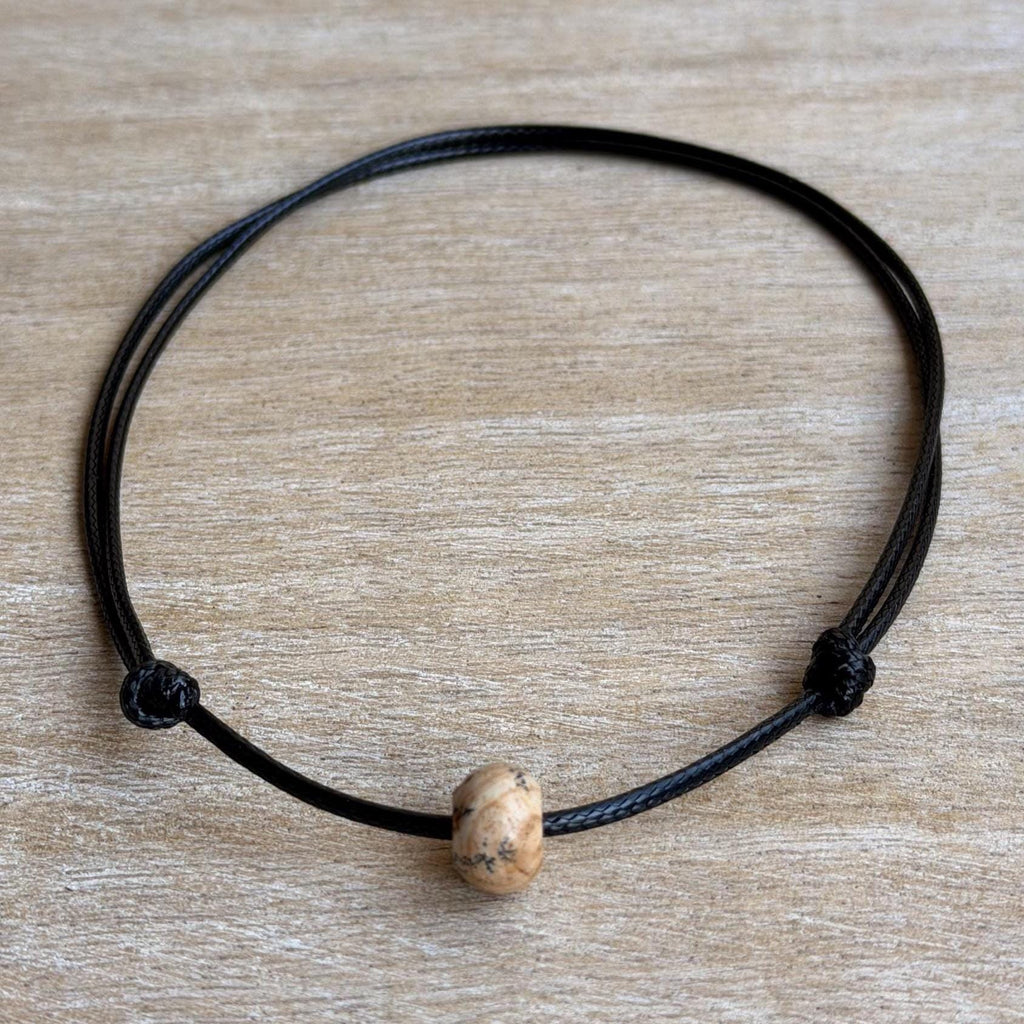 Adjustable black cord surfer choker necklace with an 8mm x 12mm natural Jasper gemstone bead, handmade unisex boho beach jewelry.