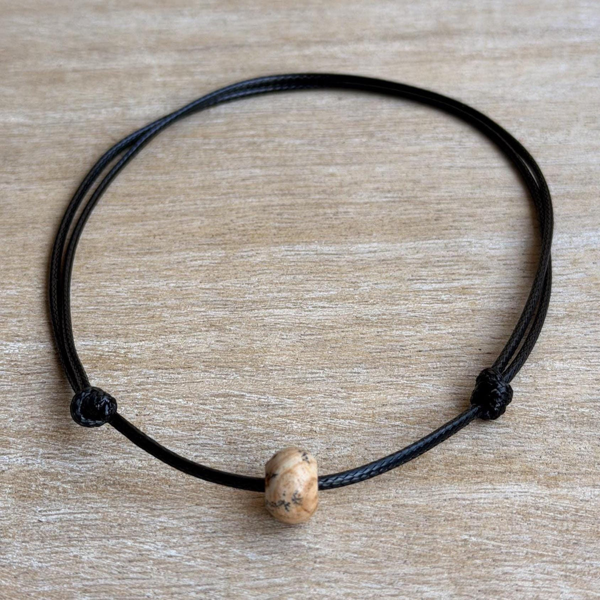 Adjustable black cord surfer choker necklace with an 8mm x 12mm natural Jasper gemstone bead, handmade unisex boho beach jewelry.