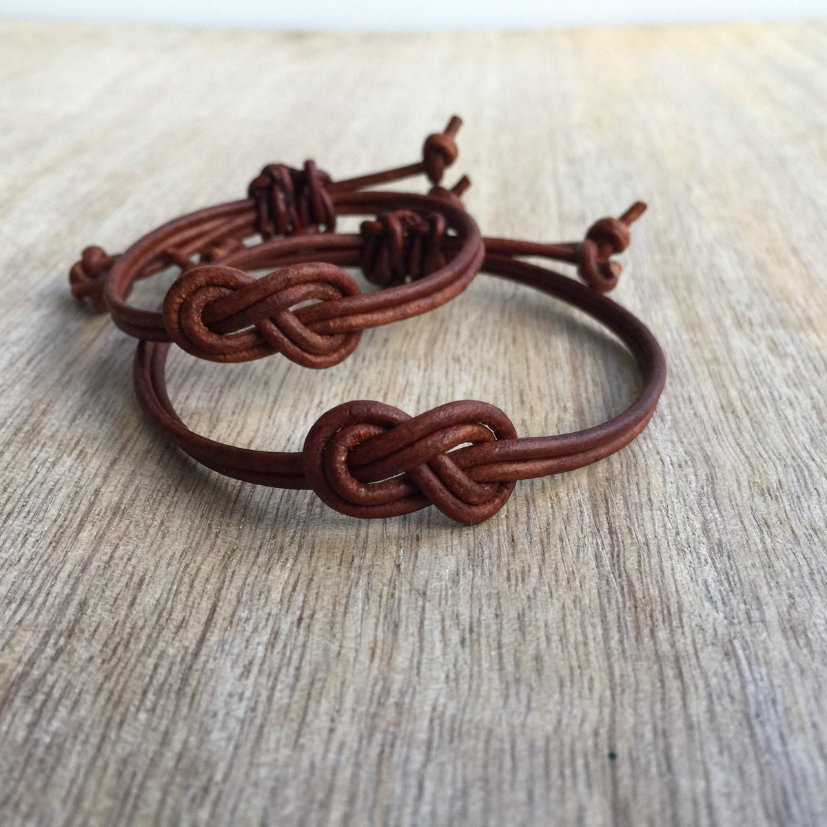 Brown leather knot his and hers couple bracelets flat lay closeup detail