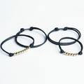 Two black braided bracelets with gold beads on a white background
