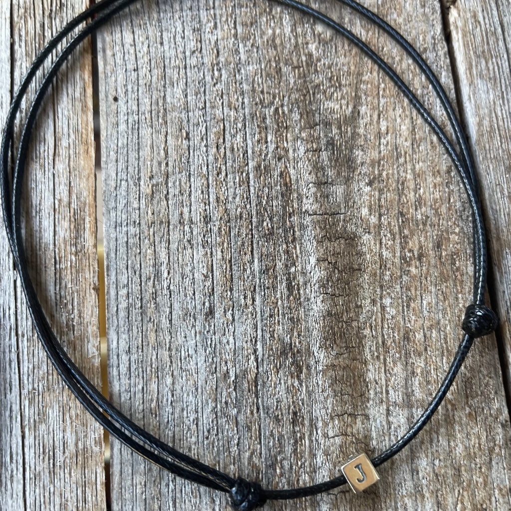 Personalized sterling silver initial cube black cord choker necklace flat lay