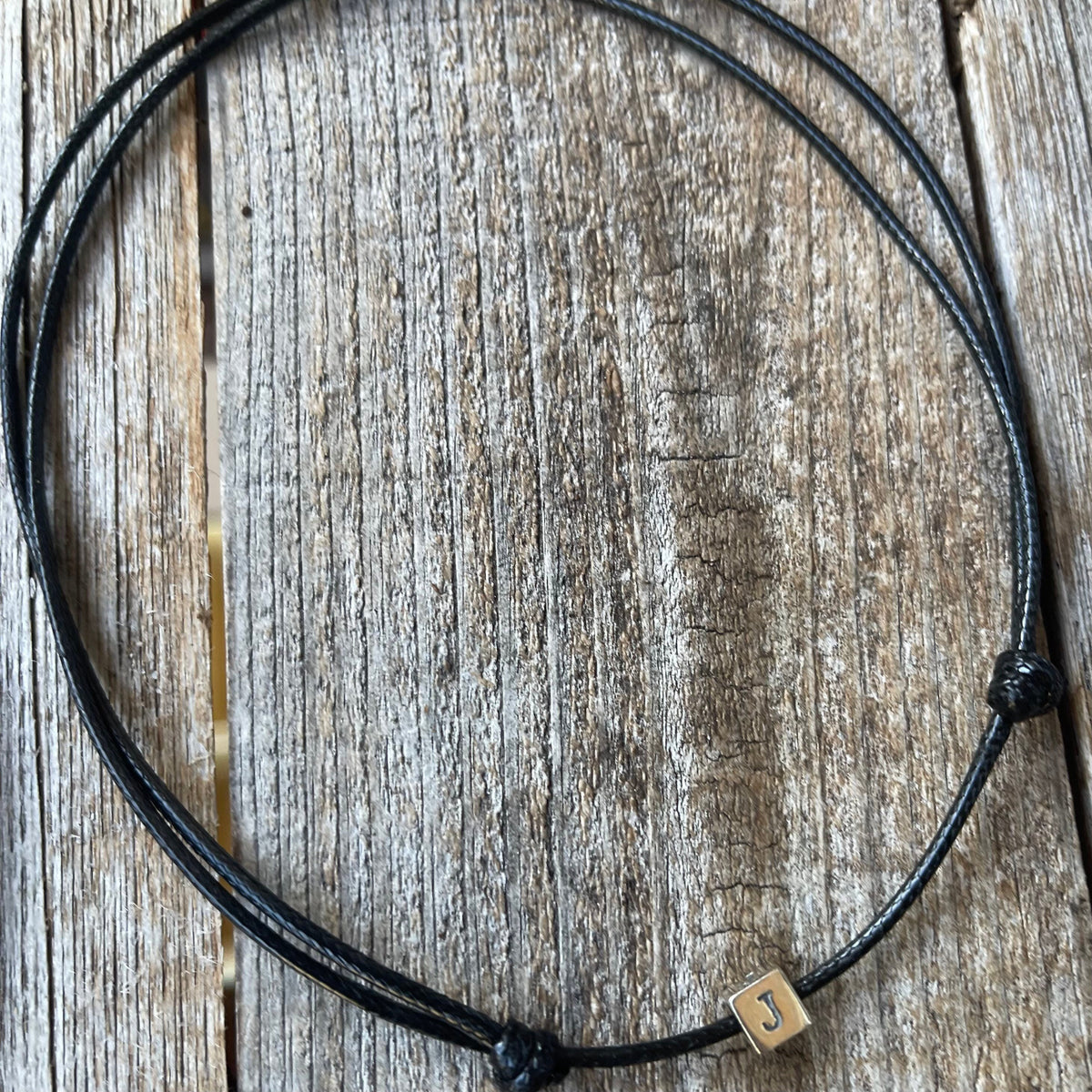 Personalized sterling silver initial cube black cord choker necklace flat lay