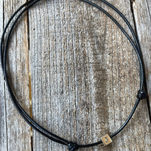 Personalized sterling silver initial cube black cord choker necklace flat lay
